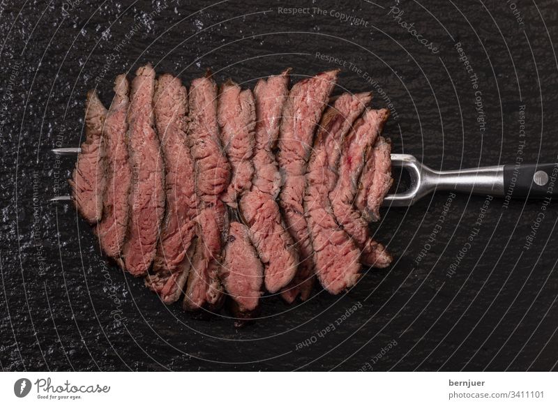 Slices of a steak on slate beef steak Carving fork Steak Butcher barbecue supervision Fat grilled Meat medium Slate Cut Fork Beef Raw Lean Black Red Juicy Stone