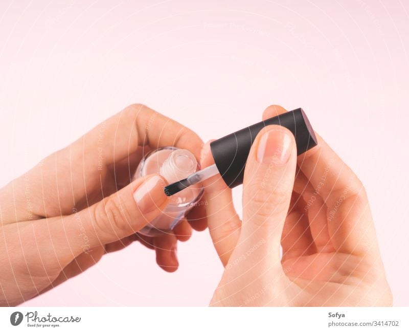Applying nude nail polish to woman's hand finger brush varnish beautiful closeup manicure care apply fingernail fashion beauty female put treatment makeup