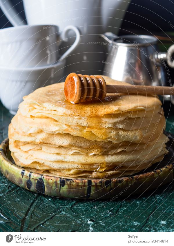 Stack of crepes with poured honey pancake stack blinis spoon tea dessert treat cook dark green background cup teapot food sweet french russian