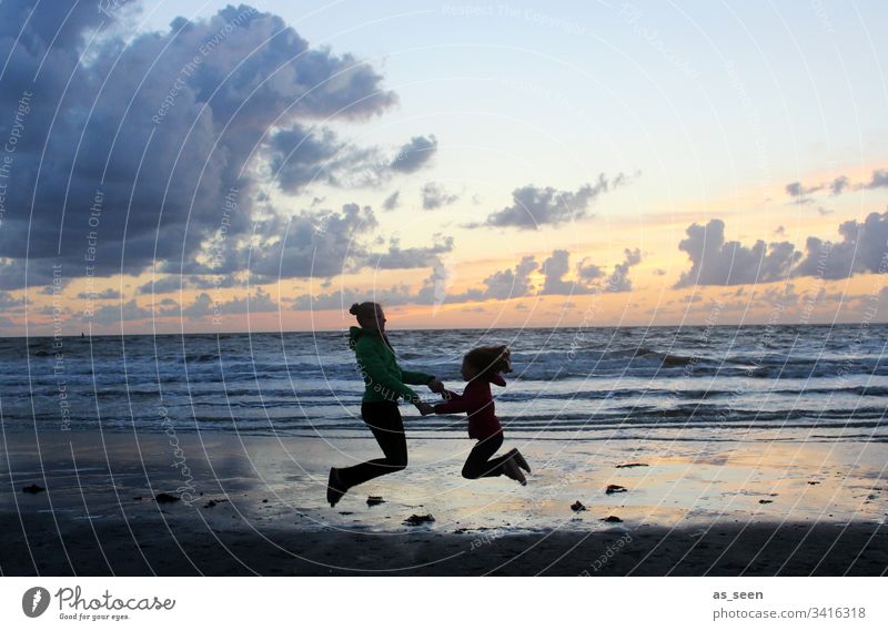 Two girls take a skydive by the sea at sunset Contrast Silhouette Child Infancy Beach Ocean Sunset Clouds jump Jump fun Freedom Joy Joie de vivre (Vitality) 2