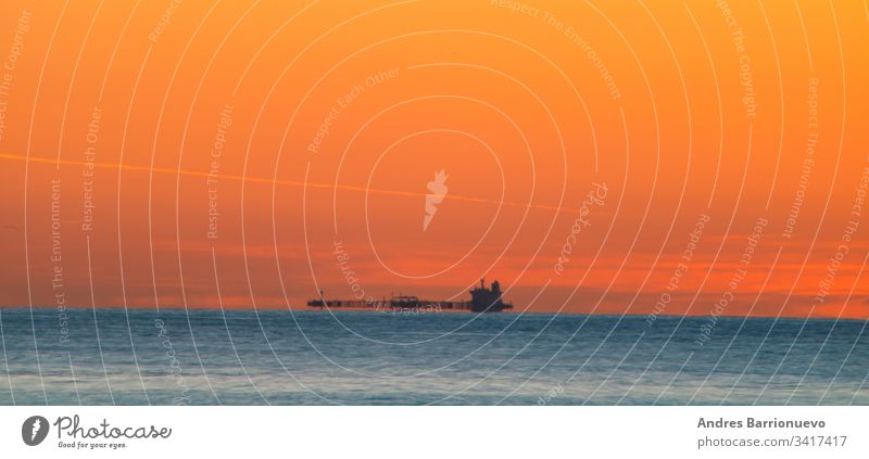 Freighter sailing at dawn travel horizon boat water nobody sea orange transportation cargo landscape ship shipping silhouette evening industrial commercial