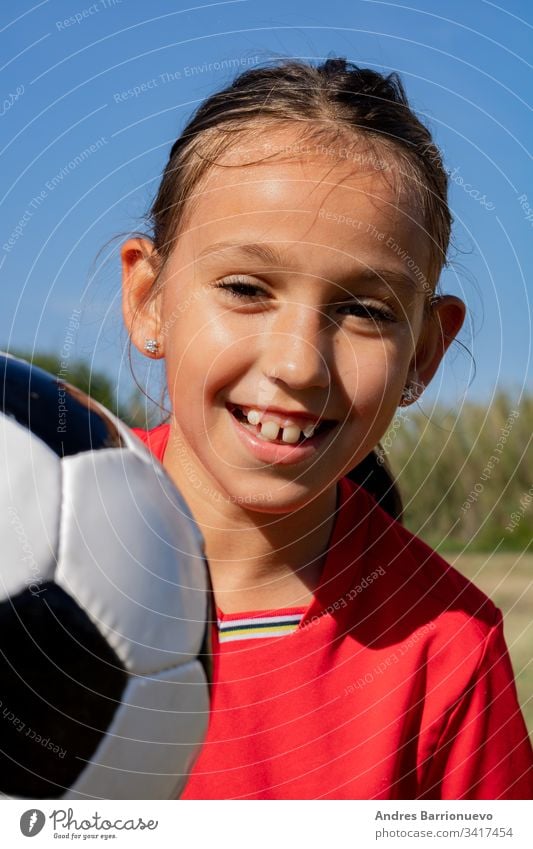 Little girl playing child little one soccer ball youth smile outside young grass kids hands on hips vertical outdoor selective focus uniform green caucasian