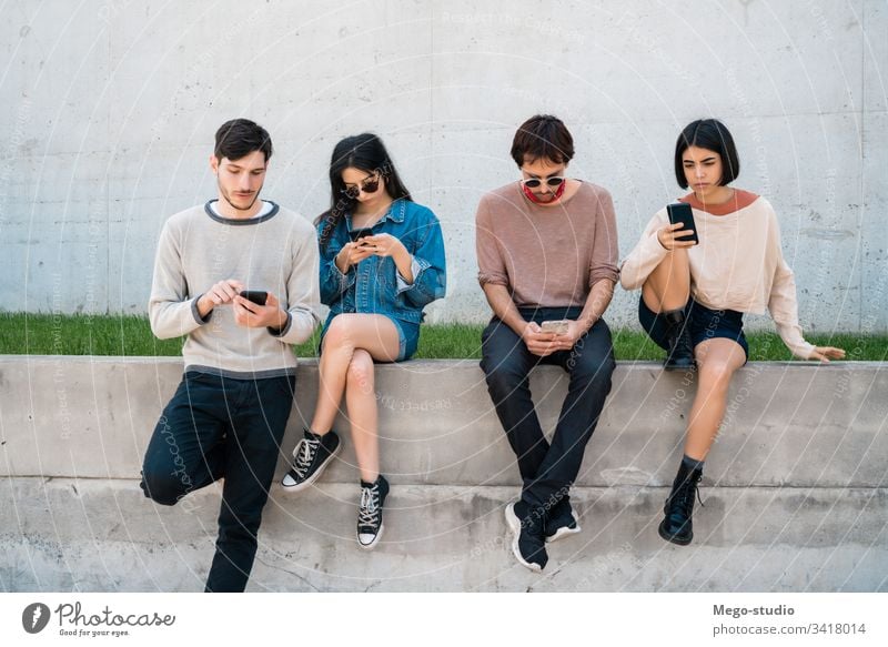 Group of friends using their phones. mobile phone friendship people young four people wireless device togetherness modern touchscreen casual connection sharing