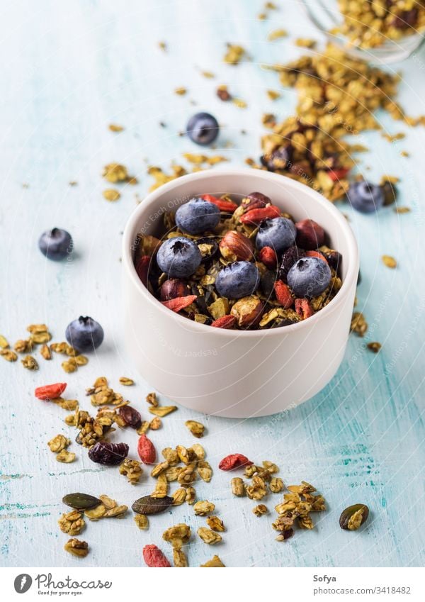 Matcha green tea granola with berries homemade matcha bowl pastel turquoise background oats goji dried fruit seeds sesame nuts healthy plant based vegan