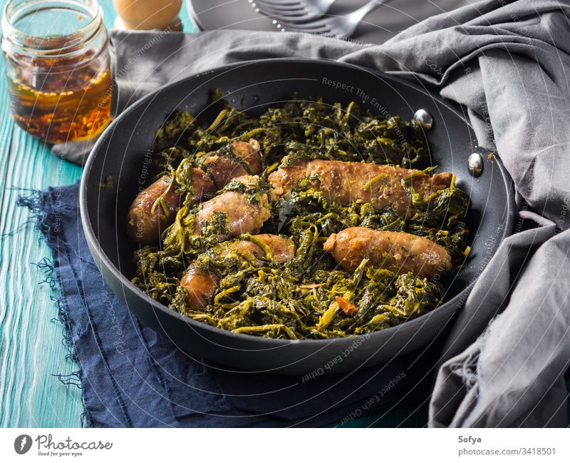 Italian sausages with rapini broccoli in a skillet meat italian kale black second dish dinner lunch meal serve table wooden set green traditional neapolitan