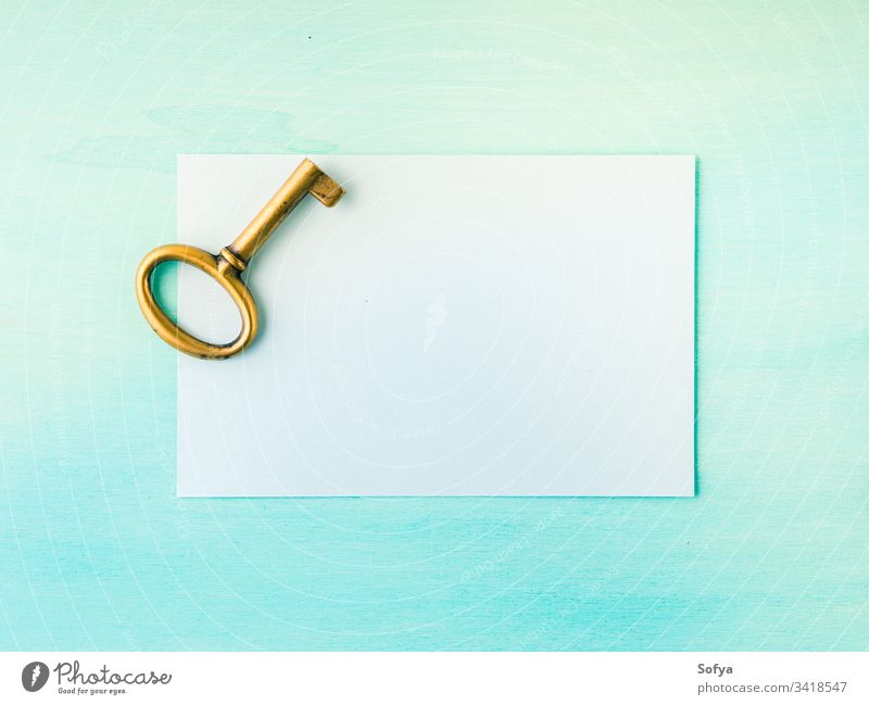 Vintage brass key and empty paper card vintage old note write blank symbol door open green pastel color background light above flat lay overhead top view page