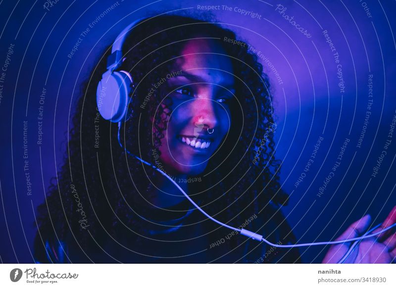 Artistic portrait with color lights of a young woman neon black art artistic cool afro afro american music headphones headset technology listening dj african