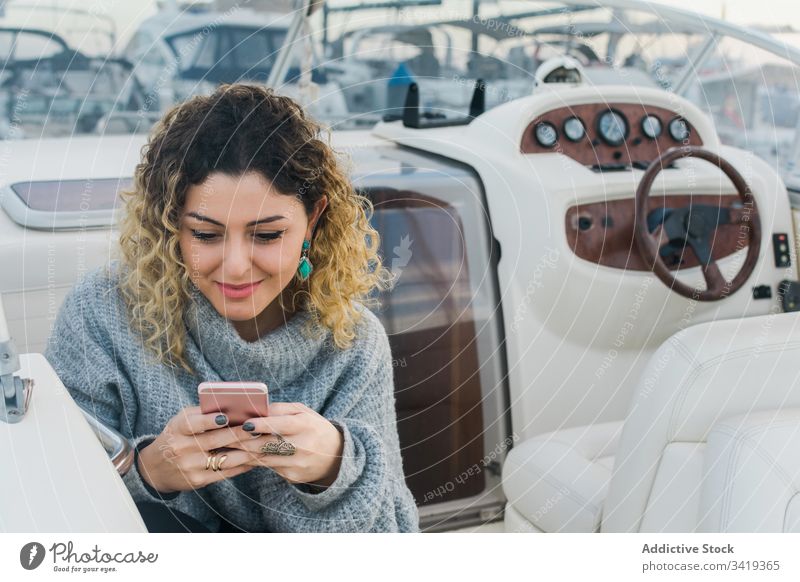 Content lady with smartphone in yacht woman using smile female browsing mobile phone laugh satisfied content enjoy surfing watch connection device gadget