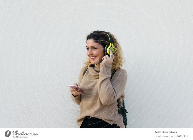 Content woman with headphones and smartphone using smile casual female laugh enjoy content listen music device gadget modern communicate connection lifestyle