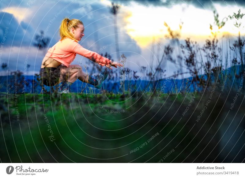 Strong sportswoman doing single leg squat in countryside exercise field sunset nature strong muscular cloudy evening female lifestyle practice training power