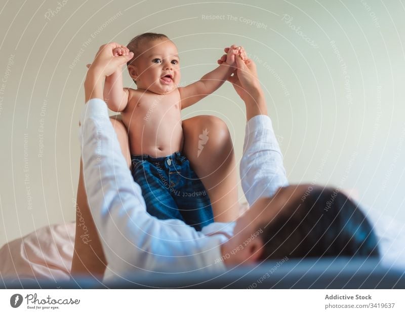 Happy faceless mother playing with baby in bedroom smile lying enjoy together child kid parent adorable love little care innocent home relax bonding rest small