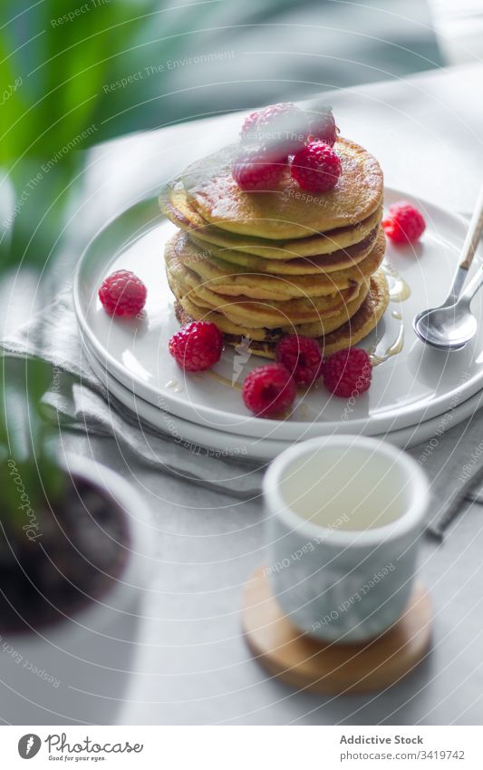 Plate with pancakes on table during breakfast raspberry morning plate napkin cup plant pot home sweet food dessert delicious tasty fresh pastry gourmet