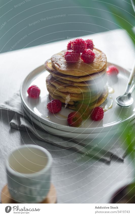 Plate with pancakes on table during breakfast raspberry morning plate napkin cup plant pot home sweet food dessert delicious tasty fresh pastry gourmet