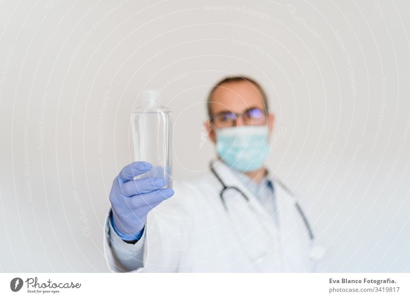 caucasian doctor wearing protective mask and gloves indoors. Holding an alcohol gel or antibacterial disinfectant. Hygiene and corona virus concept man
