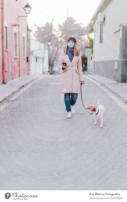 caucasian woman in the street wearing protective mask and walking with her dog. corona virus concept outdoors mobile phone technology internet public adult