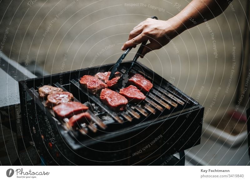 raw meat on a barbecue grill barbecuing barbeque bbq beef blood cooking dinner food grid grilled grilling heat hot human hand meal nutrition outdoors party