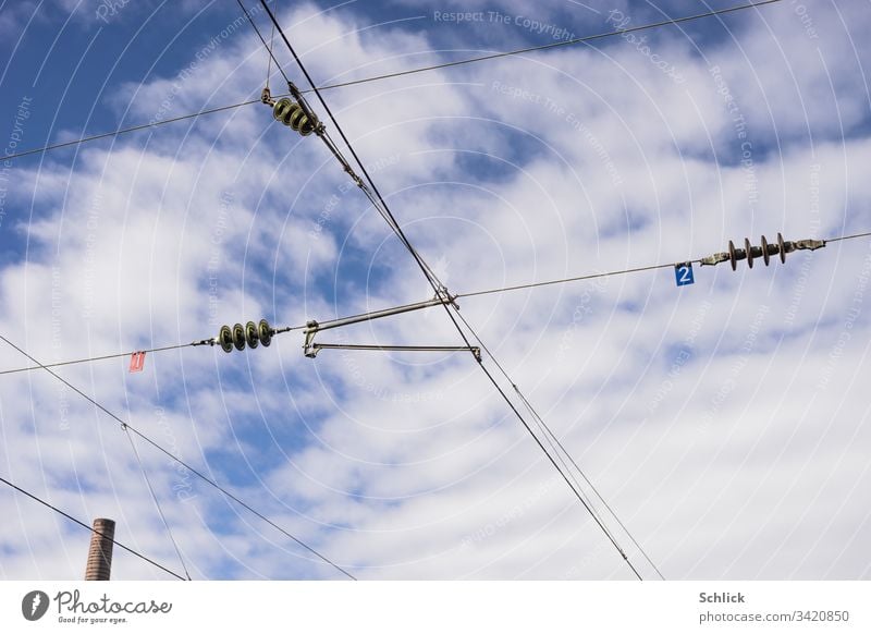 Chimney and overhead lines with glass insulators and numbers in front of blue sky with clouds Overhead contact lines Power transmission Electricity Signs