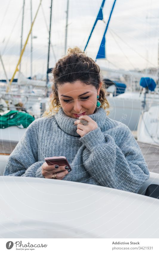 Content lady with smartphone in yacht woman using smile female browsing mobile phone laugh satisfied content enjoy surfing watch connection device gadget