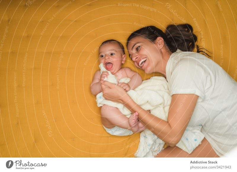 Overjoyed mother lying with baby laugh smile together enjoy child adorable little kid innocent cute happy love parent affection rest bed comfort embrace bonding