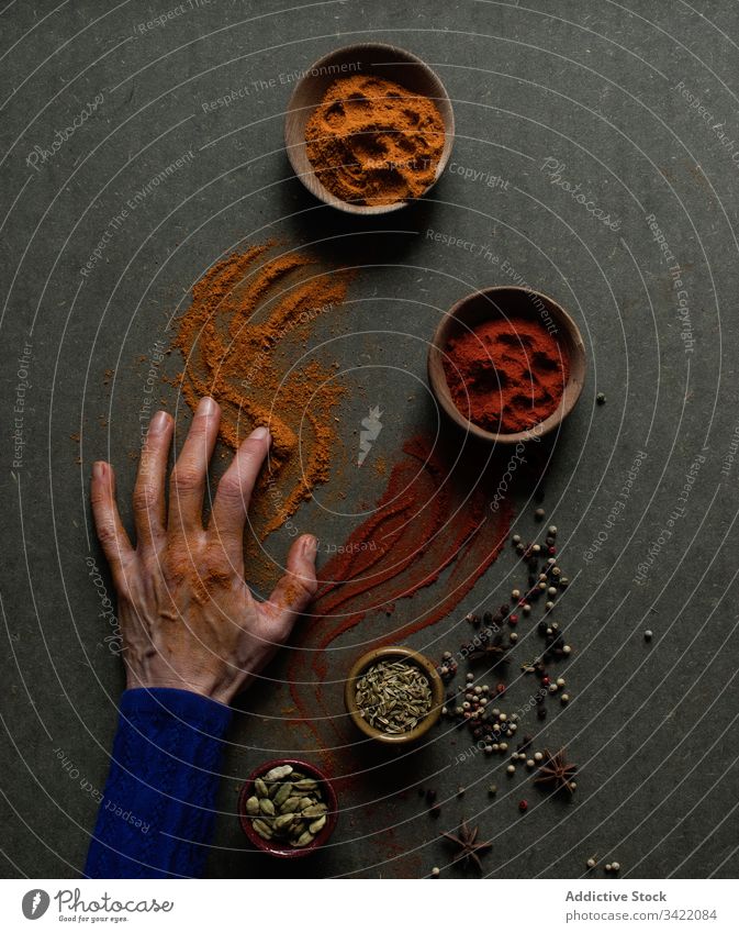 Spilled powdered spices on male hands paprika cinnamon pepper spill natural aromatic condiment seasoning culinary food chili ground bowl pot person creative