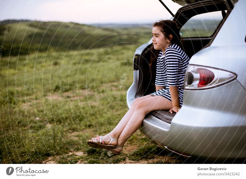 Little girl sitting in open trunk of car trip travel child happy journey tourist vacation happiness nature childcare enjoying daughter carefree break transport