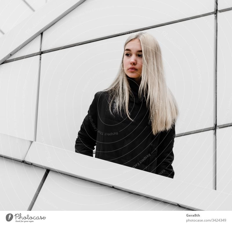 young girl with blond hair and black clothes against a gray building adult architecture autumn blonde city dreamy erase girl blonde hairstyle house lines look
