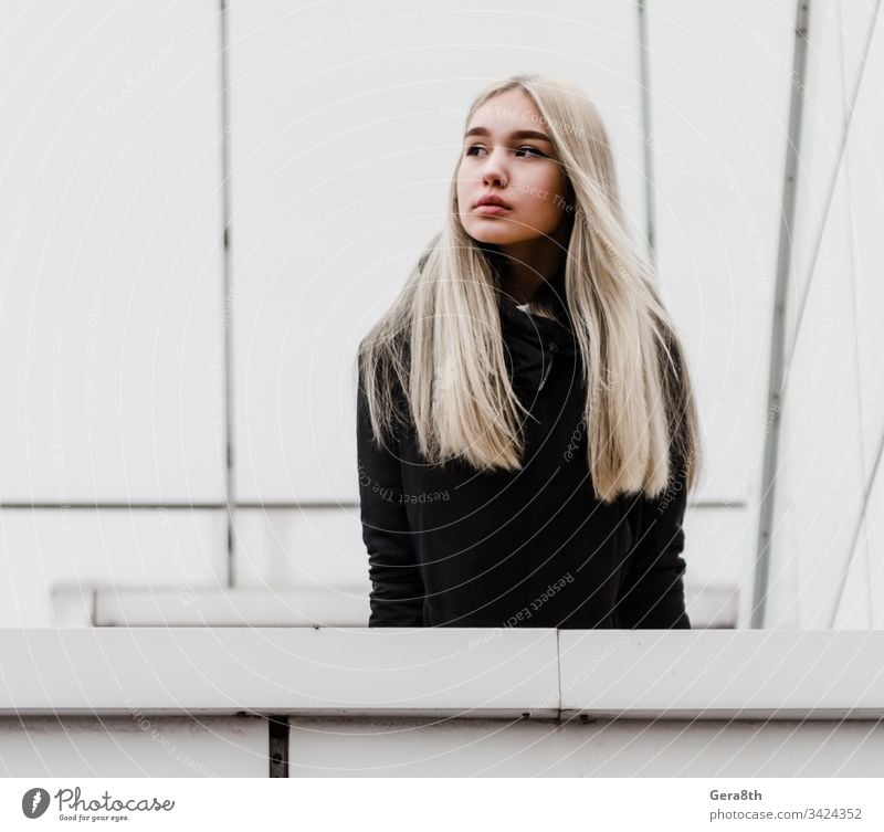 young girl with blond hair and black clothes against a gray building adult architecture autumn blonde city dreamy erase girl blonde hairstyle house lines look