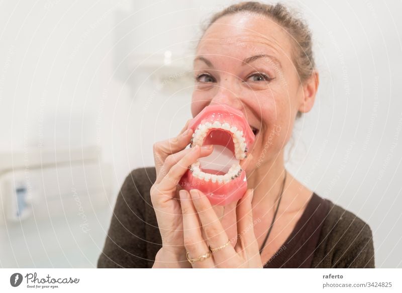 Funny woman playing with jaws in dentist clinic Dentist fun open medicine mouth horizontal dentistry face toothbrush female girl people cary humor clean teeth