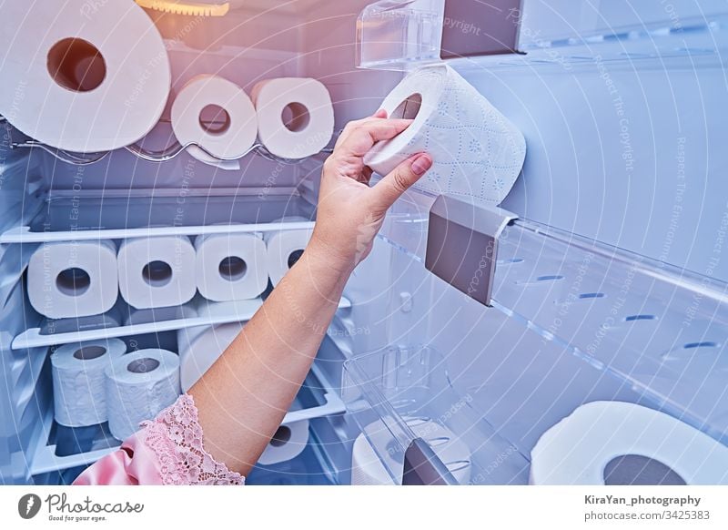 Female hand takes roll of toilet paper from refrigerator door coronavirus covid-19 woman fridge kitchen household prank tissue home towel wc napkin sanitary