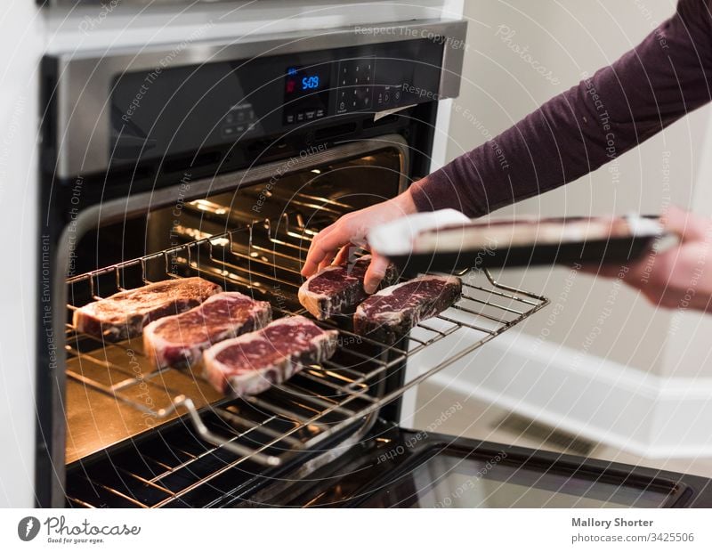 Man putting steaks into oven raw steak beef raw beef cooking cooking steak man man cooking cooking steaks in oven red meat cooking meat kitchen home