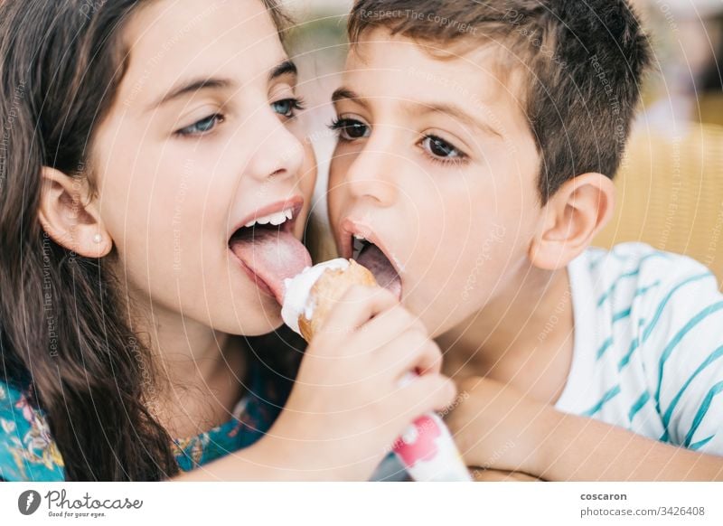 Two little kids eating an ice cream together beautiful boy cafe caucasian cheerful child childhood children close up cute delicious dessert emotion enjoy