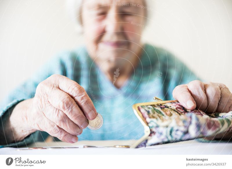 Concerned elderly woman sitting at the table counting money in her wallet. senior pensioner poverty retirement old empty coins background miserable broke lonely