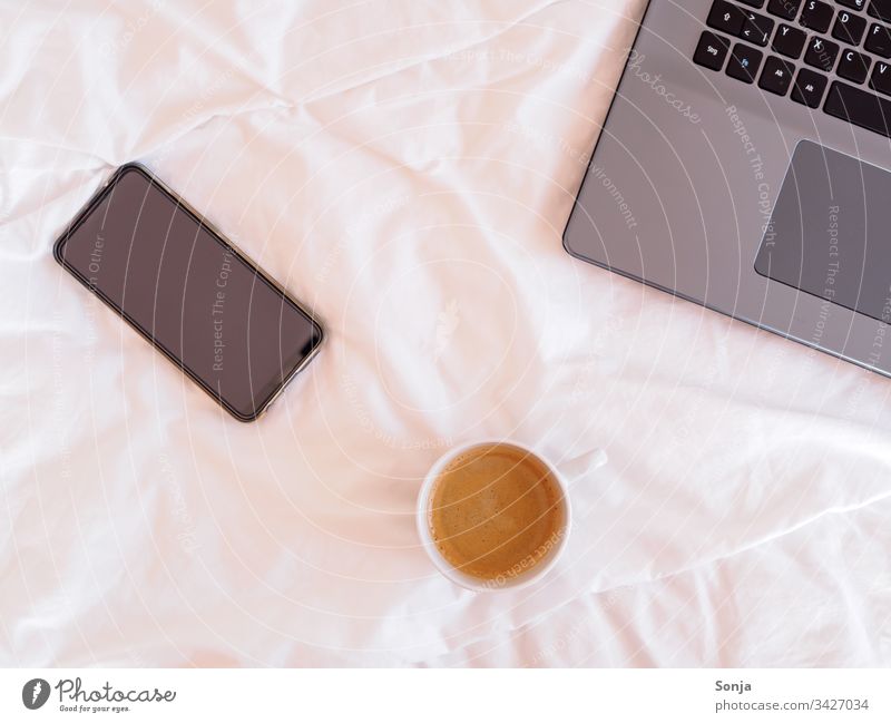 Laptop, Smartphone und eine Tasse Kaffee auf einer weißen Bettdecke, Home office laptop smartphone home office technology lifestyle computer business Internet