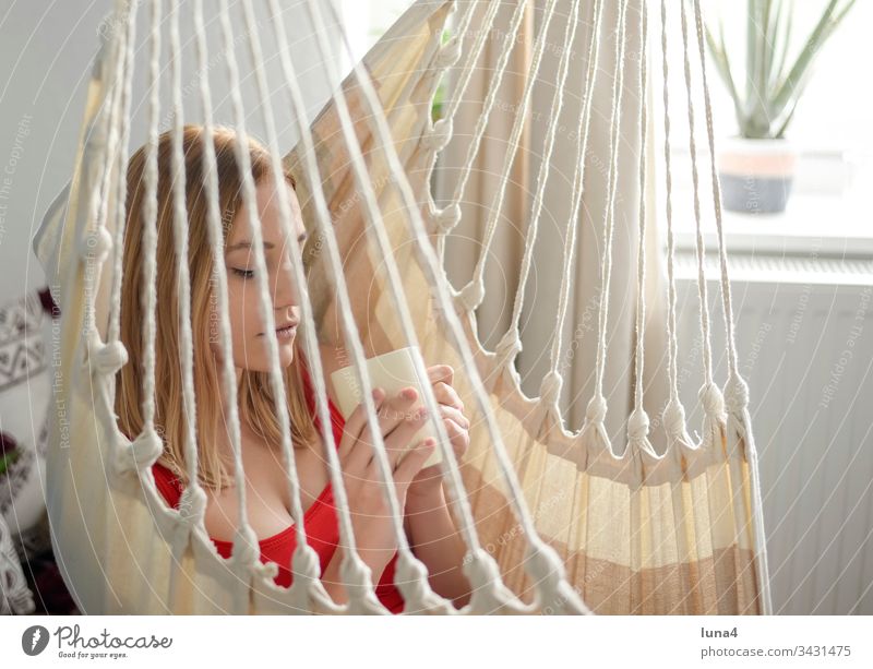 young woman with cup in hammock Woman Hammock Cup Dreamily room Coffee melancholically Tea Drinking Beverage Meditative Coffee cup food Smiling sensual To enjoy
