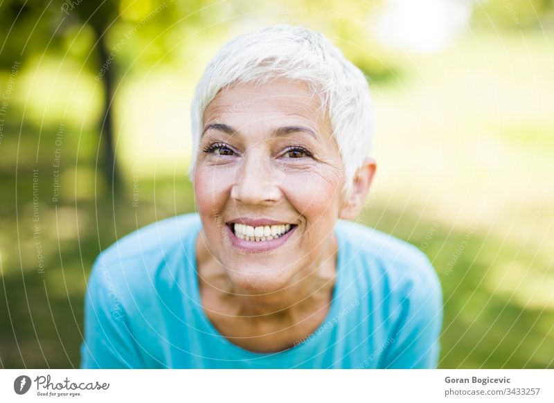 Portrait of a smiling sporty senior woman in a park smile female caucasian portrait person healthy fitness active happy gray lifestyle hair elderly outside