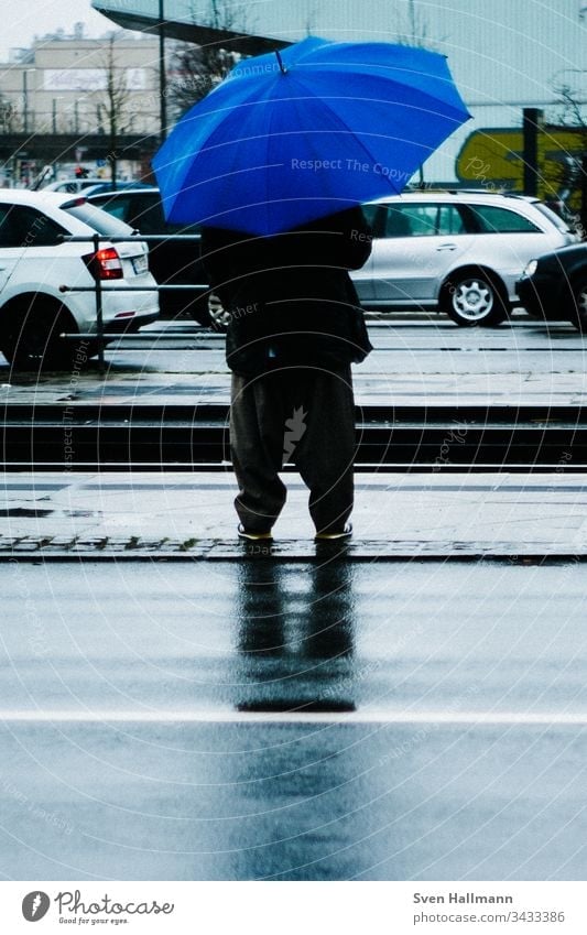 Man with blue umbrella is waiting Blue Umbrella baggy Stop (public transport) cars Wait Human being Rain Adults Bad weather Colour photo Weather Exterior shot