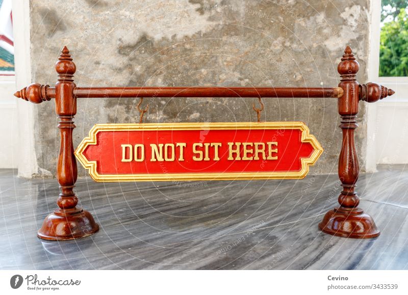Sign Do not sit here sign Warn Assignment interdiction dunning Temple Buddha Buddhism Buddhist religion Belief Superstition red background Gold Marble floor