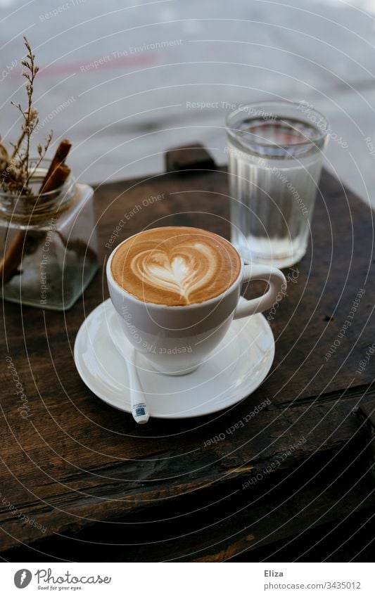 A cup of cappuccino with a latte art heart on a wooden table in a café Cappuccino Coffee Café latte type Heart Cup Table Wood TableWood table Beverage Breakfast