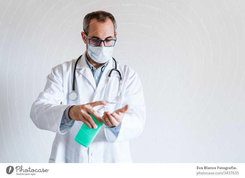 doctor man wearing protective mask indoors. Holding an alcohol gel or antibacterial disinfectant. Hygiene and corona virus concept. Covid-19 professional