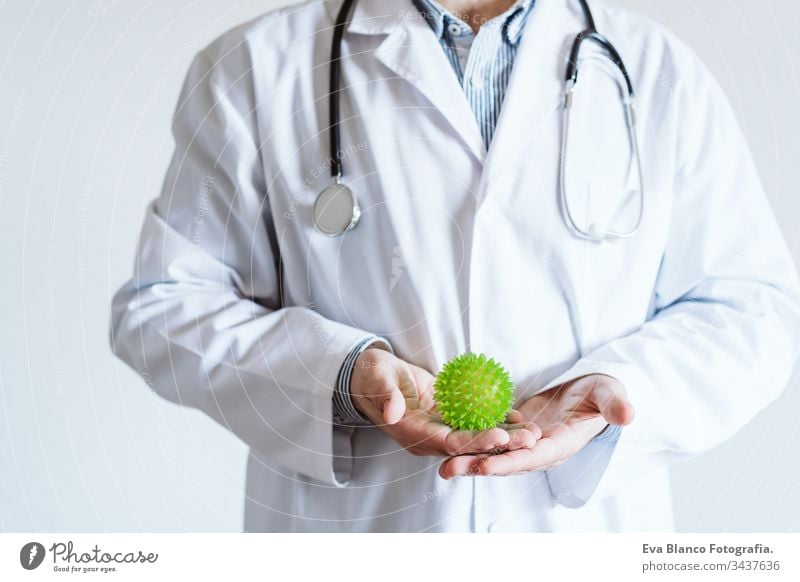 doctor man wearing protective mask indoors. Holding a green ball looking as coronavirus. Covid-19 concept professional corona virus hospital working infection