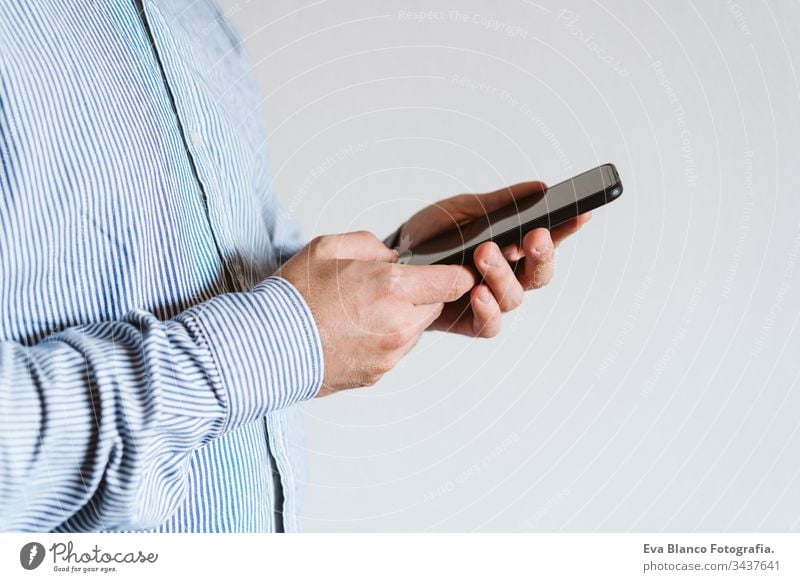 close up view of a man using mobile phone indoors. Technology concept unrecognizable technology wireless shirt working internet texting finger executive