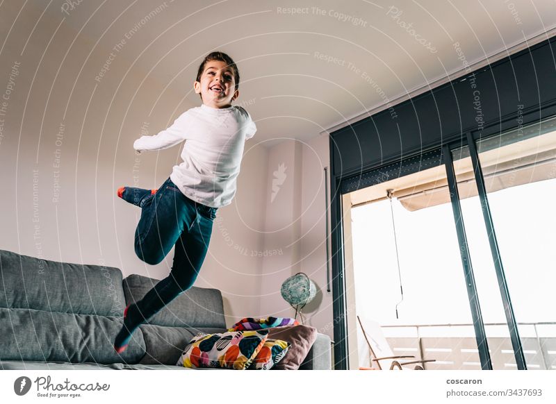 Funny kid jumping off the couch action adorable alone beautiful casual caucasian cheerful child childhood copy space cute domestic life energy enjoyment