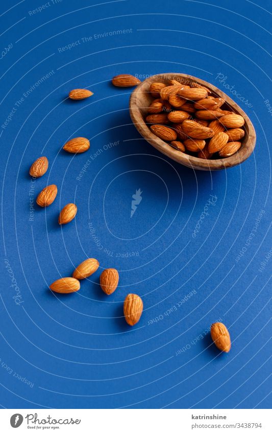 Fresh almonds in a bowl on a blue background classic blue diet minimal negative space copy space nuts wooden food fresh healthy ingredient natural nutrition