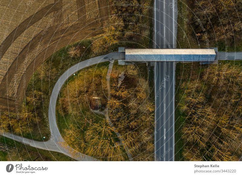A street with a pedestrian bridge taken from a vertical top view by a drone Street Aerial photograph Deserted Exterior shot Day Traffic infrastructure