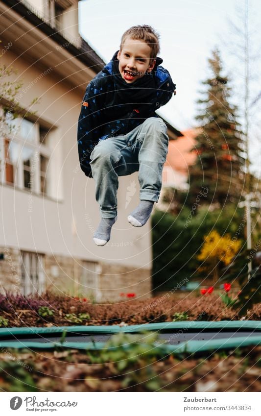 Little boy laughs and jumps on a trampoline in the garden of a house Boy (child) Small Child Schoolchild Trampoline Hop Jump Flying Garden