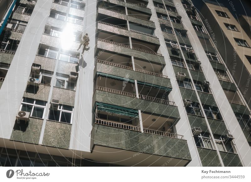worker cleaning windows of a high-rise apartment block in Rio de Janeiro, Brazil building business city cleaner climb climbing dangerous exterior facade glass