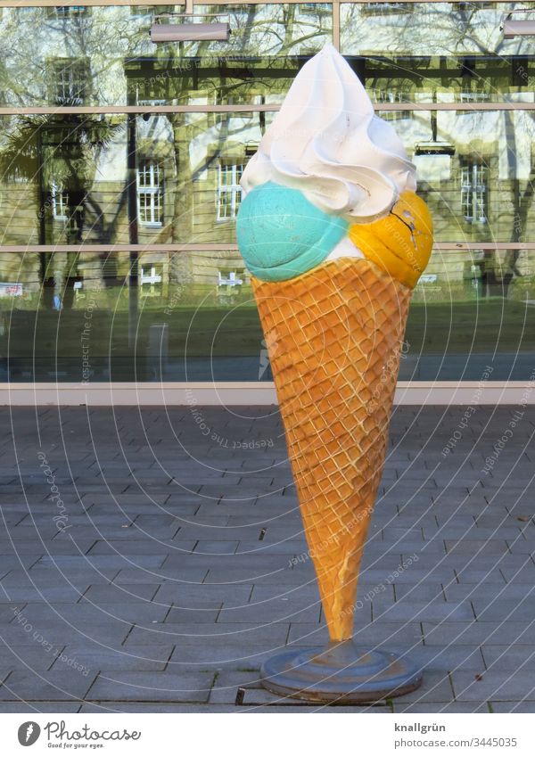 Ice cream advertisement in the form of an oversized wafer croissant with a pistachio green and a mango yellow ice cream scoop with whipped cream on top sweets