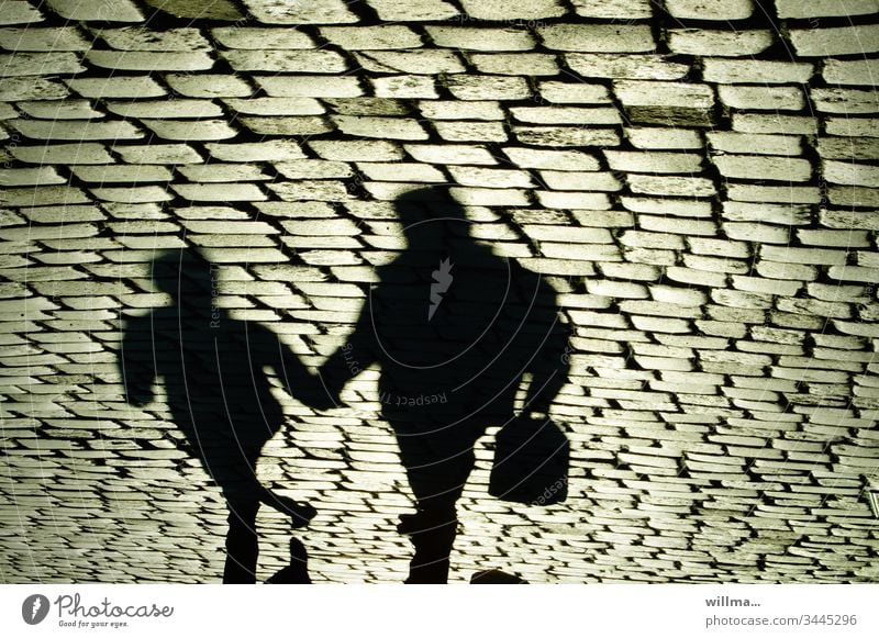 Shadow of two people on the cobblestone Shopping trip city stroll persons Human being Paving stone two persons Hold hands Together Father and Child