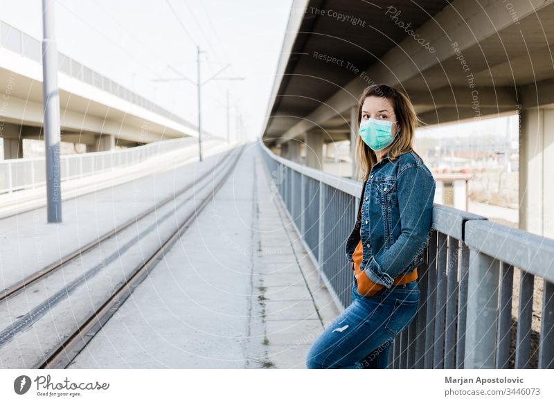 Young woman with a surgical mask in an empty tram station alone biohazard care caucasian city contagion coronavirus covid-19 covid19 danger disease epidemic