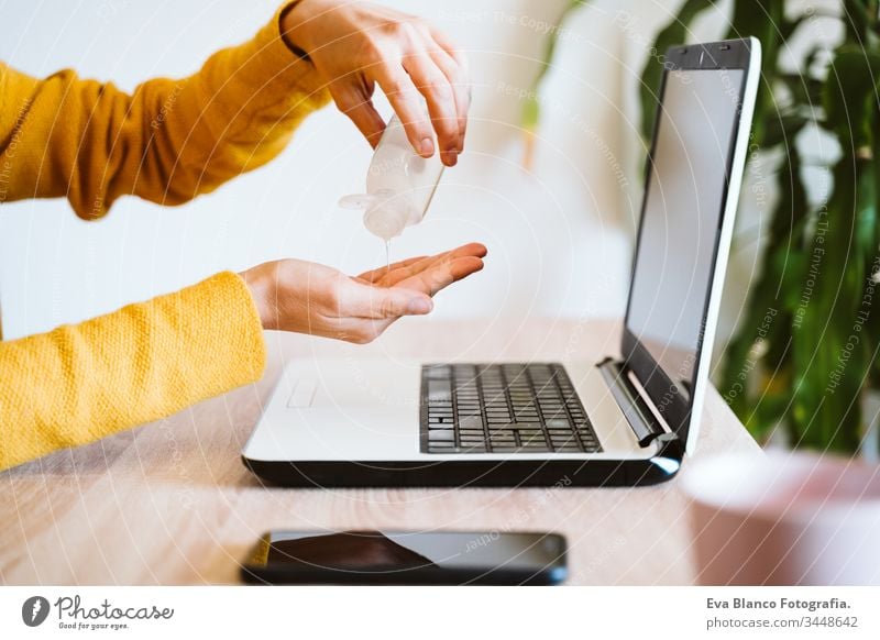 young woman working on laptop at home, using hand sanitizer alcohol gel. Stay home during coronavirus covid-2019 concept disinfectant hands antibacterial